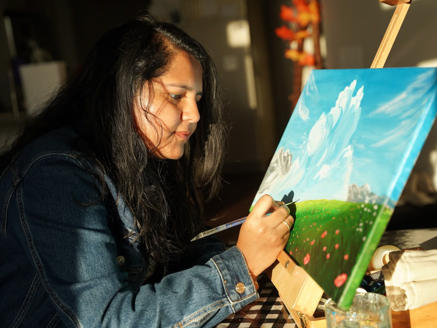 Keziah painting at her easel in golden light